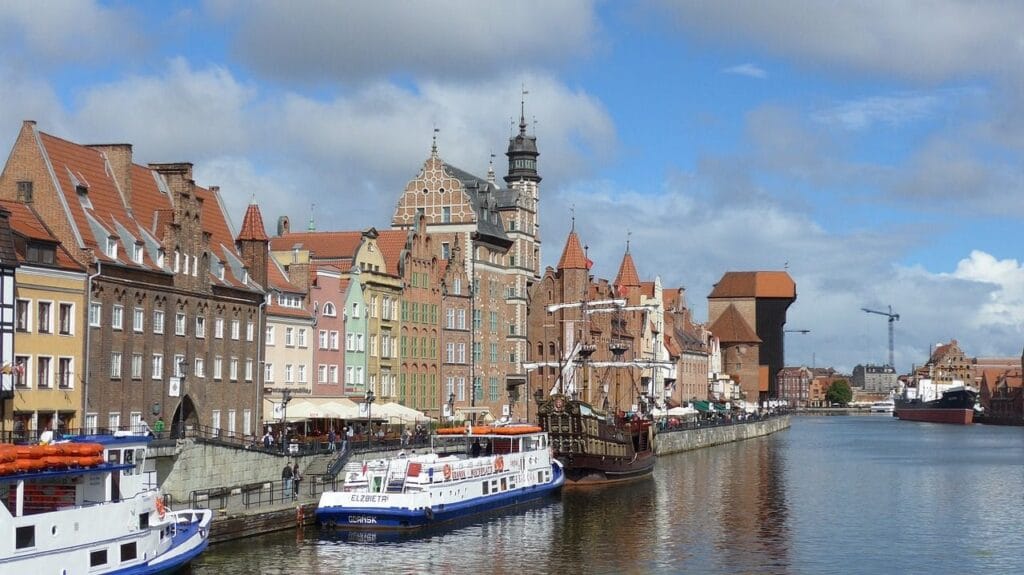 Historic buildings by the river in sunshine.