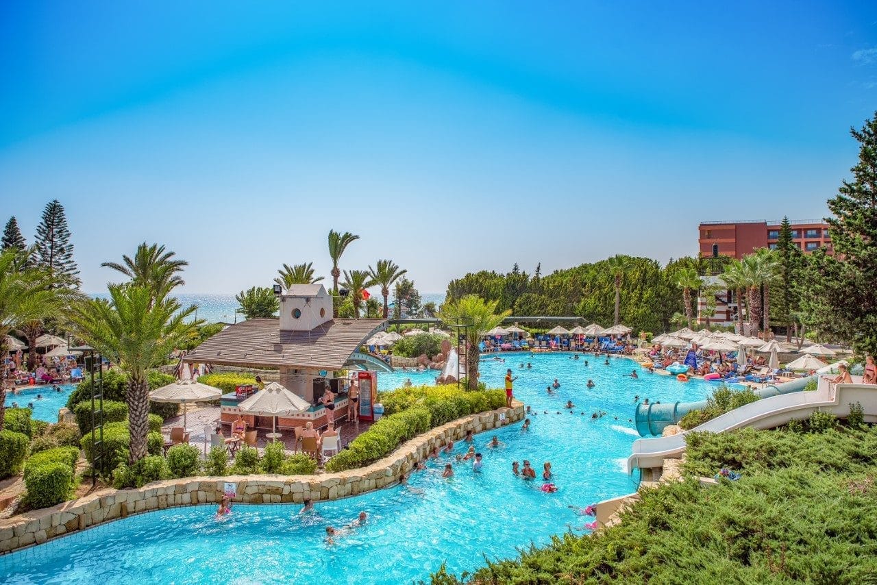 Poolområde med palmer och människor.