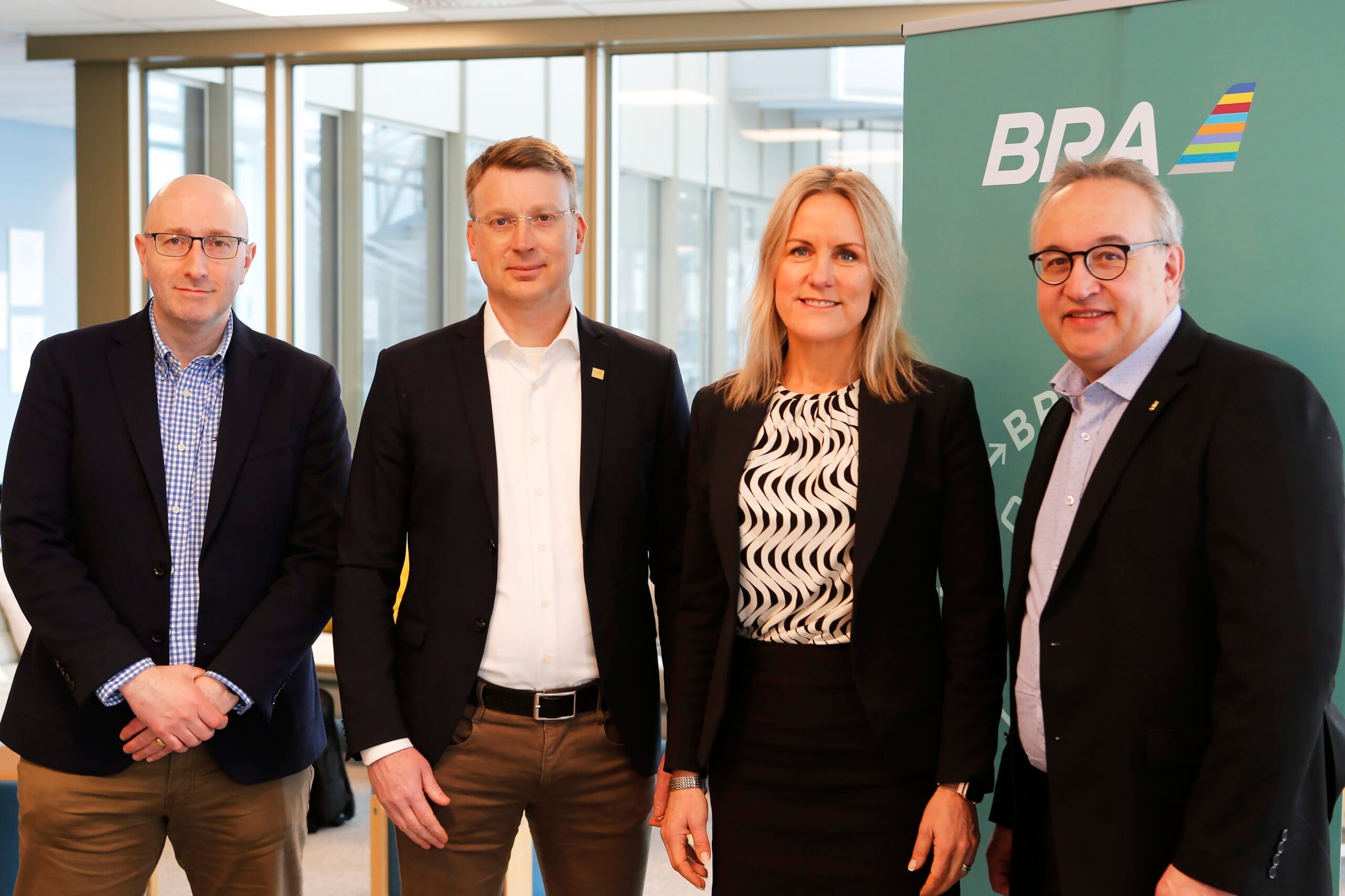 Fyra personer framför BRA-skylt.