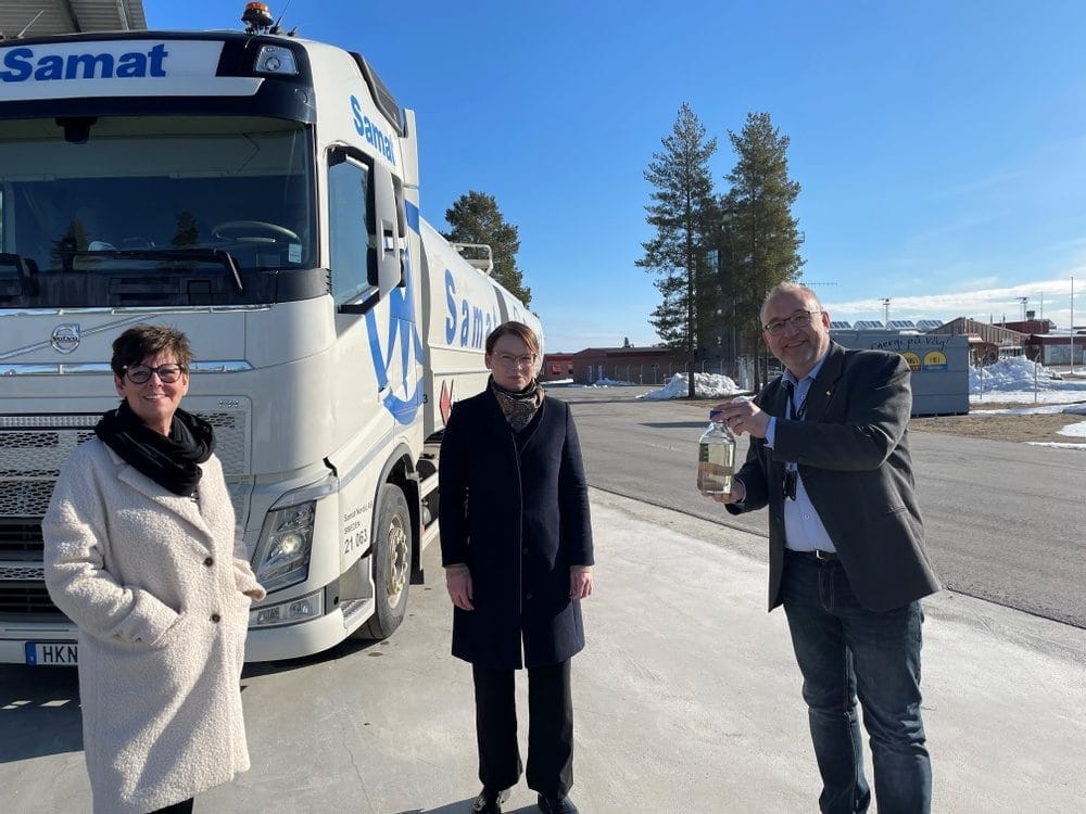 Three people in front of a truck outdoors.