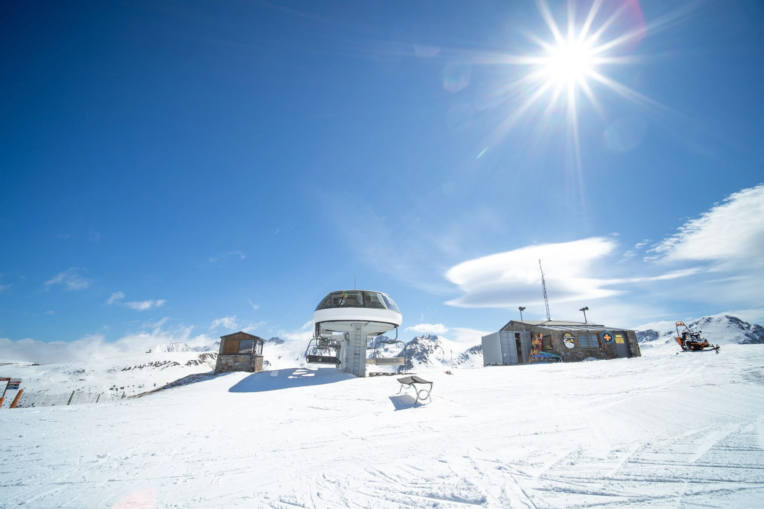 Sunny day on the ski slope with snow-covered mountains.